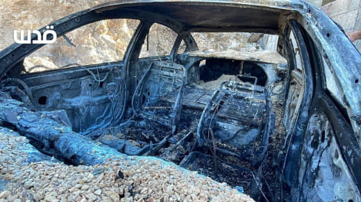 Residents assess the damage after Israeli settler militias set fire to several Palestinian vehicles and sprayed racist g