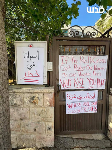 Palestinian protesters place banners on the office of the International Red Cross in the city of Al-Bireh, the occupied 